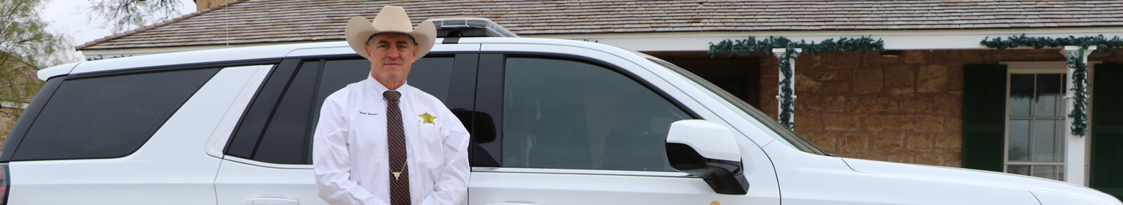 Tom Green County Sheriff Nick Hanna standing in front of Sheriffs Office Vehicle